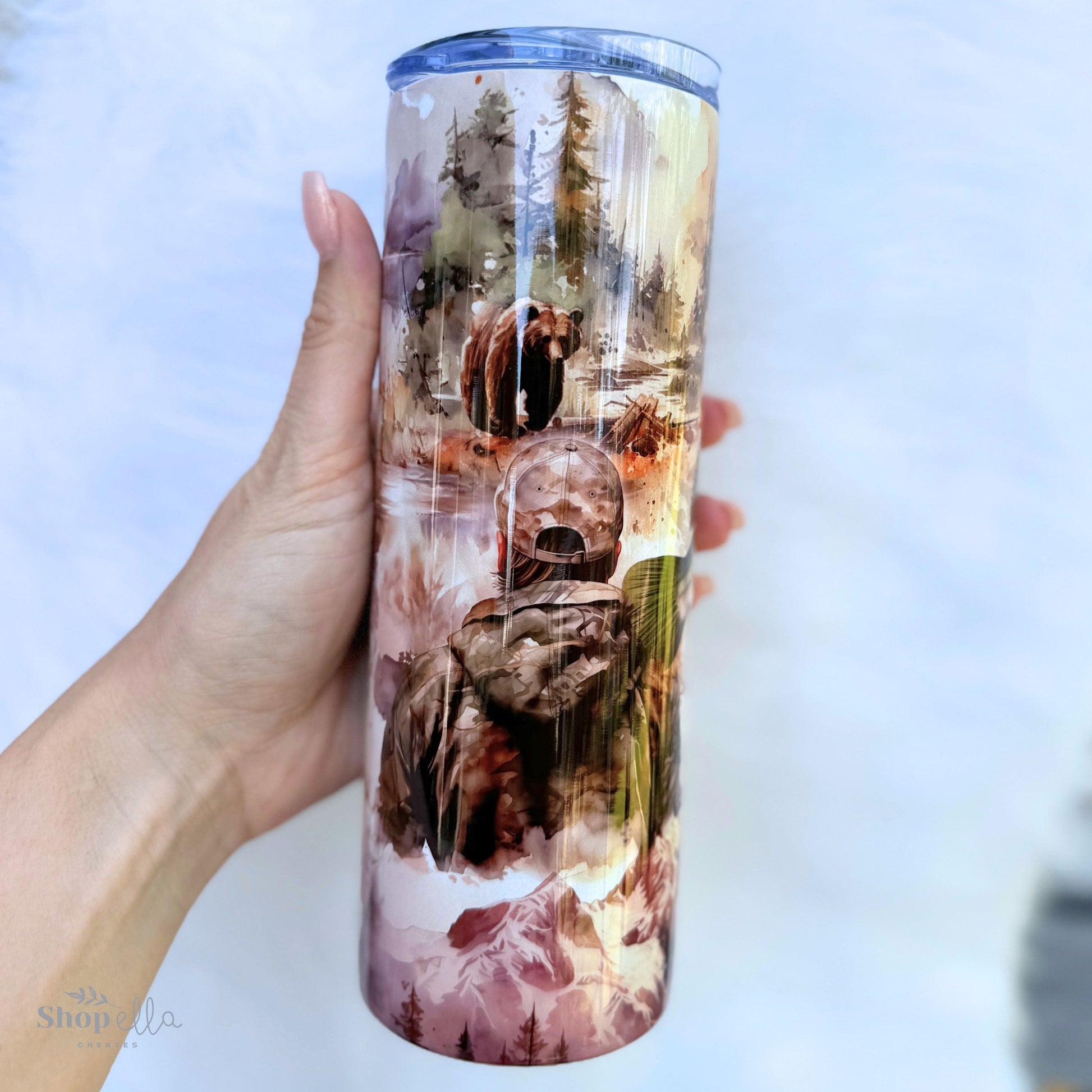 a person holding a tumbler with a picture of a hunter and bear on it