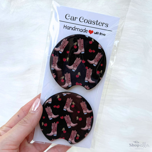 a pair of car coasters with cowgirl boots and coquette cherries on a black background