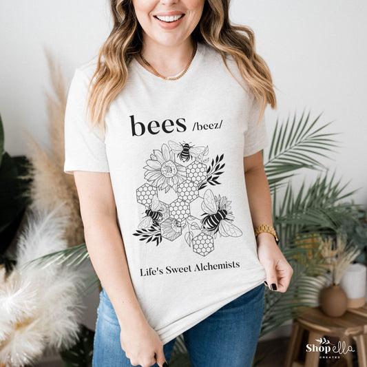 white shirt with black design that says bees with a beautiful image of 3 honey bees and honeycomb and flowers and leaves under design says life's sweet alchemists