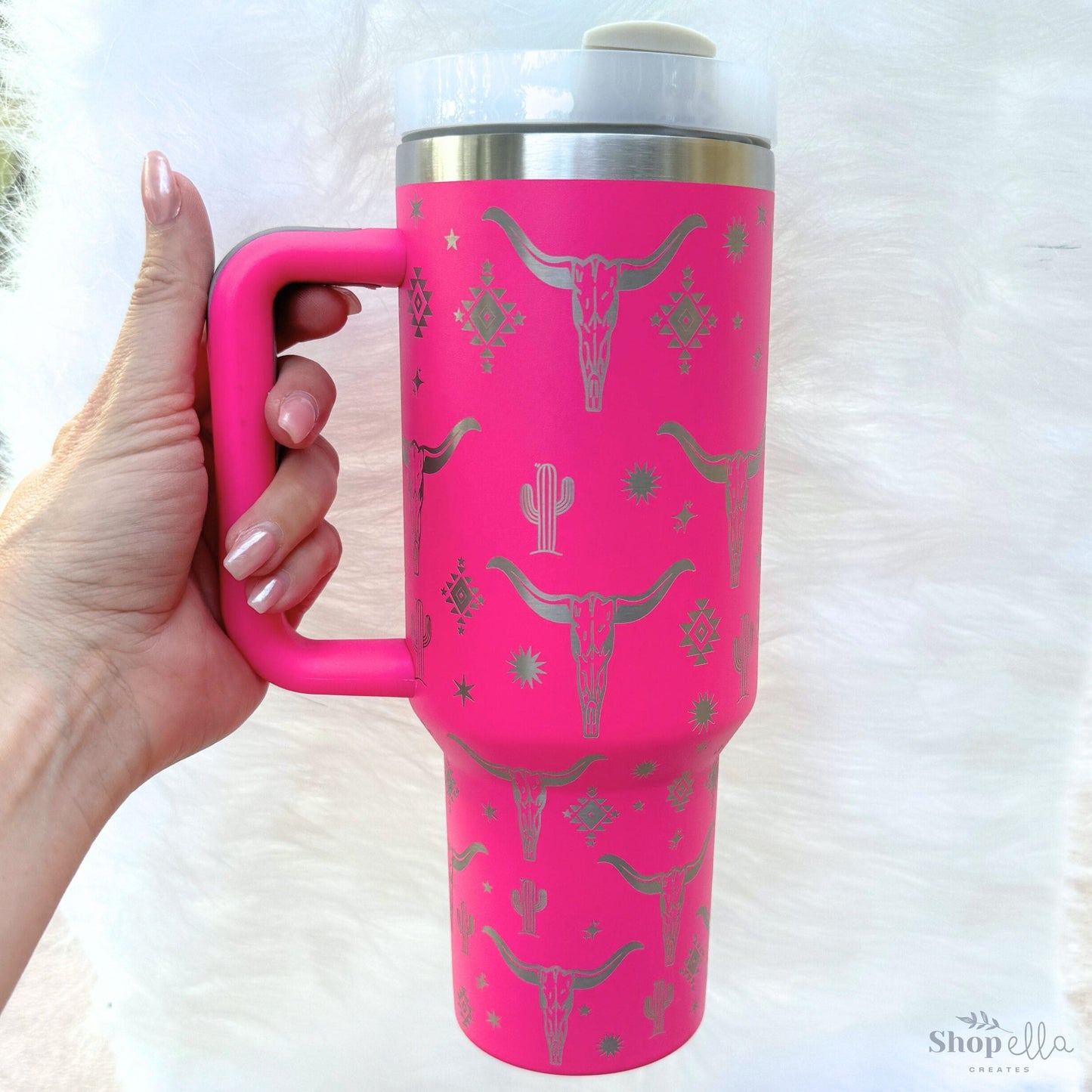 a woman's hand holding a pink travel mug