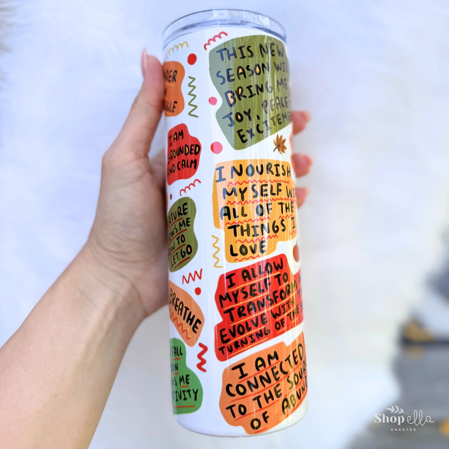 a hand holding a white 20oz skinny tumbler with lid a cup of fall affirmations