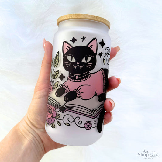 a hand holding a white can with a black cat on it