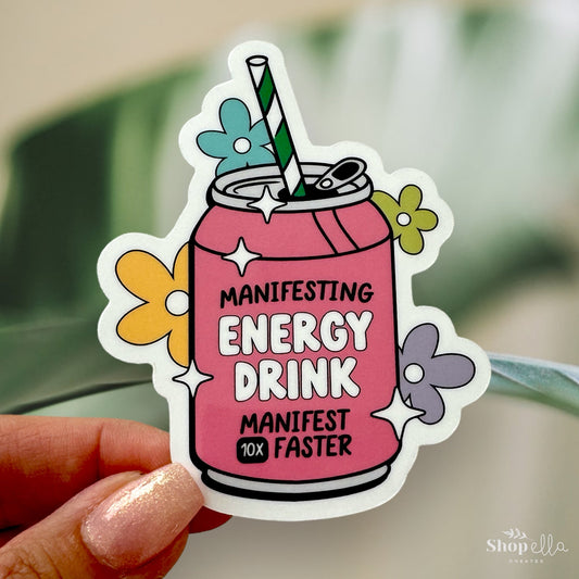 a sticker of a pink drink with a green straw that says manifesting energy drink manifest 10x faster