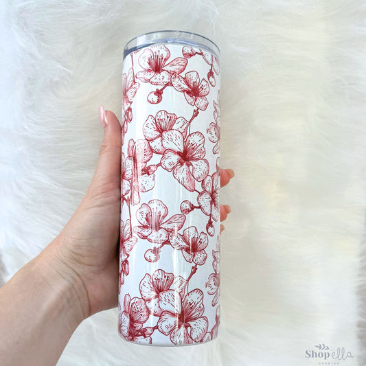 a hand holding a red and white floral tumbler