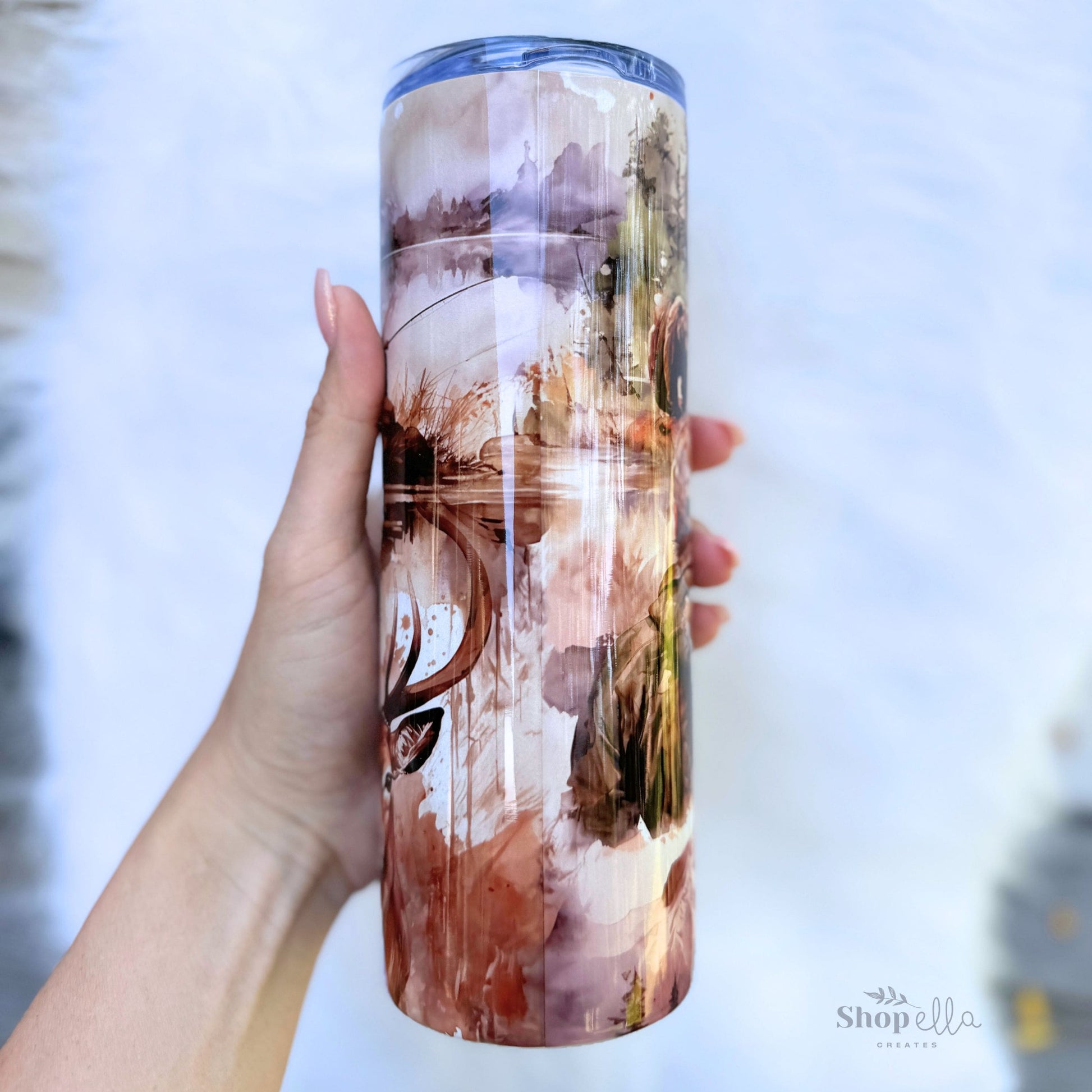 a hand holding a white 20oz skinny tumbler with lid with hunting and fishing images for men