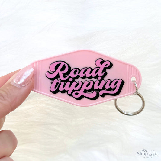 a pink keychain with the words road tripping on it